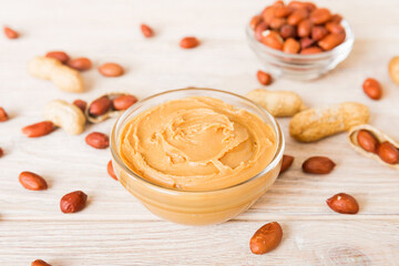 Bowl of peanut butter and peanuts on table background. top view with copy space. Creamy peanut pasta in small bowl