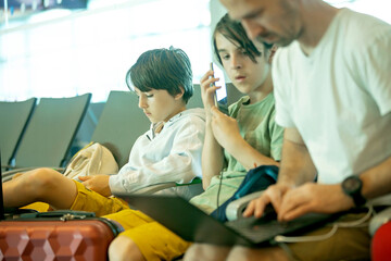 Children, brothers, traveling for summer holiday, waiting at the airport to board the aircraft