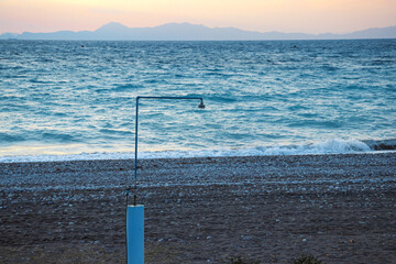 Outdoor beach shower in front of the ocean at Paralia Ixia beach during sunset