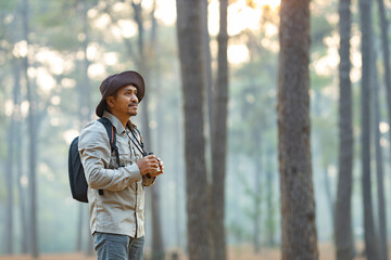 Bird watcher is looking through binoculars while exploring in the pine forest for surveying and...