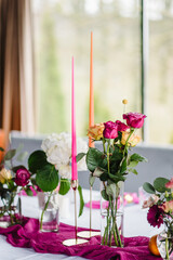 Decoration with pink and orange flowers roses and candles and fruits. Beautifully organized event, served table banquet ready for guests in hall. Table set for a birthday party or wedding reception.