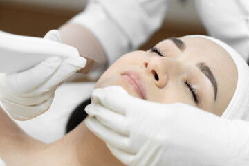 Naklejka premium The photo shows how ultrasonic facial cleansing from this professional cosmetologist helps to get rid impurities, excess seborrhea and sebum, creating healthy and fresh look of skin in beauty clinic