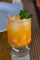 glass of tangerine caipirinha garnished with mint leaf