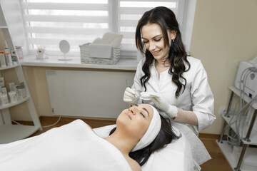 The process of deep cleansing of facial skin is presented, during which a young woman is in a calm and comfortable environment, enjoying professional skin care in a beauty clinic.