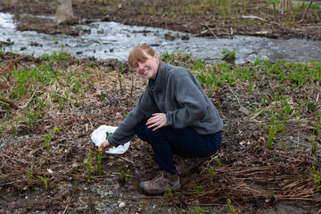 A young woman harvesting fresh fiddleheads by river in New Brunswick, Canada.