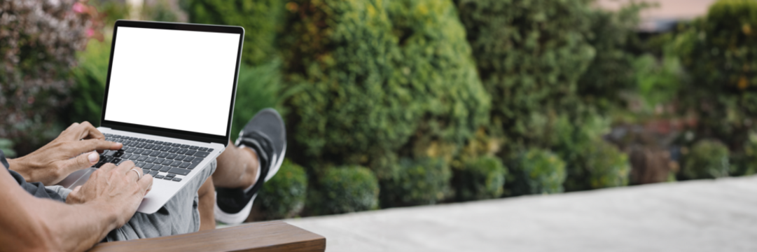 a man works in nature, sitting in a chair with a laptop