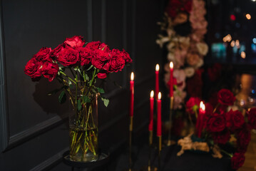 Luxury candle light dinner table setup for couple on Valentine's day. Table setting in restaurant. Location decoration red flowers and decor with candles for surprise marriage proposal. Romantic date.