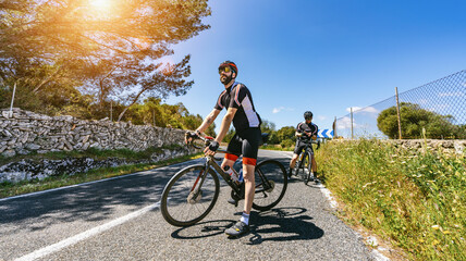Fototapeta na wymiar Mature Adult on a racing bike climbing the hill at mediterranean sea landscape coastal road