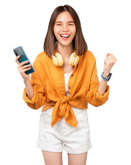 Cheerful young Asian woman in headphones and holding smartphone with fists clenched celebrating...