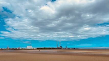 Large sandy beach and blue clouds. Day. Port. Factories