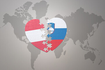puzzle heart with the national flag of slovenia and austria on a world map background.Concept.