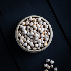 Roasted white chickpeas in wooden bowl, traditional Turkish nut on dark background. Turkish leblebi, famous nut, stack of yellow white roasted chickpea.