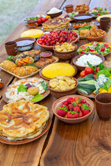 Homemade Romanian Food with grilled meat, polenta and vegetables Platter on camping. Romantic traditional moldavian food outside on the wood table.