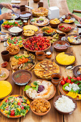 Homemade Romanian Food with grilled meat, polenta and vegetables Platter on camping. Romantic traditional moldavian food outside on the wood table.