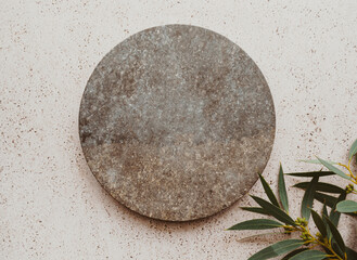 Marble gray round podium and green eucalyptus branch on beige texture background