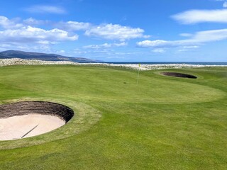 A closeup view of a green and pot bunker on a classic links style course in Brora, Scotland in the...