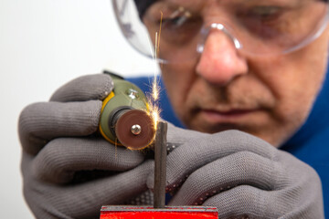 Male locksmith Worker processes metal with engraving drill.