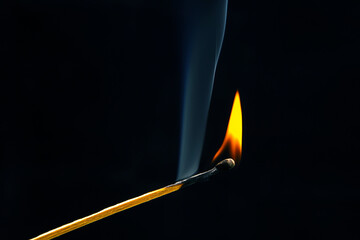 Flashed and burning wooden match on a dark background close-up. Bright fire and smoke from a...