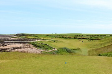 An incredible view of a classic links golf hole with pot bunkers in Scotland with the ocean in...