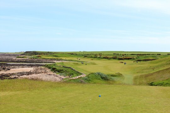 An incredible view of a classic links golf hole with pot bunkers in Scotland with the ocean in nearby outside of St. Andrews, Scotland