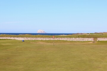 An incredible view of a golf hole in Scotland with the ocean in the background in North Berwick,...