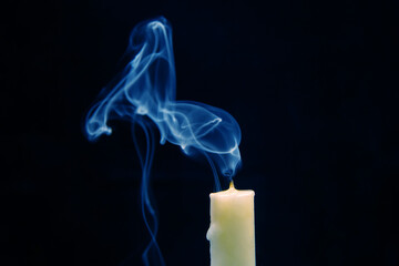 Smoke from an extinguished candle on a dark background. The concept of spirituality and the end of...