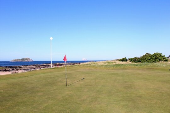 An incredible view of a golf hole in Scotland with the ocean in the background in North Berwick, East Lothian, Scotland