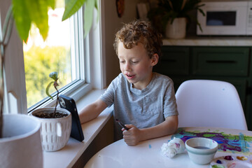 A happy young boy while using his smartphone and painting on the side.