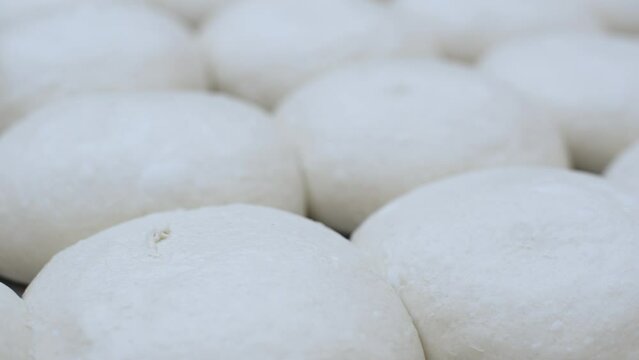 Close-up of balls of fresh raw dough for baking buns or other wheat flour products, on the kitchen table. Blank for baking