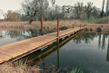 Fototapeta na wymiar A small wooden bridge over a narrow stream. A small river with a wooden bridge over it