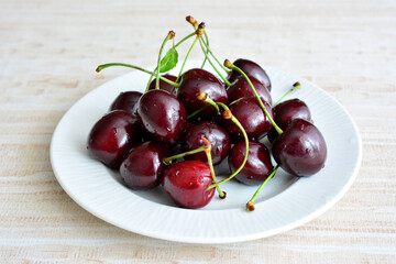 group of big cherries with water drops on white saucer isolated, copy space  