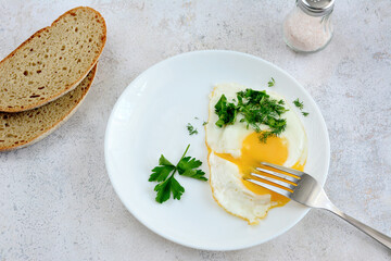 fried egg on white plate with fork and two slices of bread