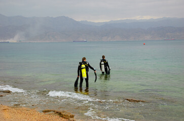 Eialt, Israel. Two friends (unidentified; back view) going to dive. Coral Beach Nature Reserve in Eilat, one of the most beautiful coral reefs in the world, is a famous tourist and diver attraction.