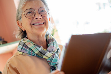 Smiling senior woman wearing eyeglasses relaxing at cafe table reading menu, leisure time