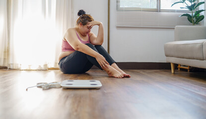 Obese Woman with fat upset bored of dieting Weight loss fail  Fat diet and scale sad asian woman on weight scale at home weight control.