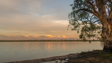 A cloud bank reflected on the calm waters of a lake in the evening in the Australian countryside.