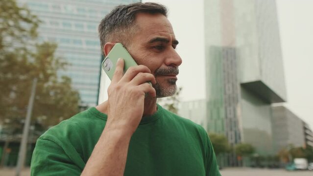 Close up, middle aged men talking on mobile phone on modern buildings background