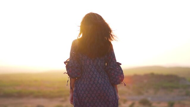 Rear view of Indian girl standing on top of the hill and looking at sunset at Bhuj, Kutch, India.  Female tourist on summer vacation.