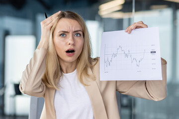 Close-up photo. Portrait of a frustrated business woman who looks sadly into the camera, holds...