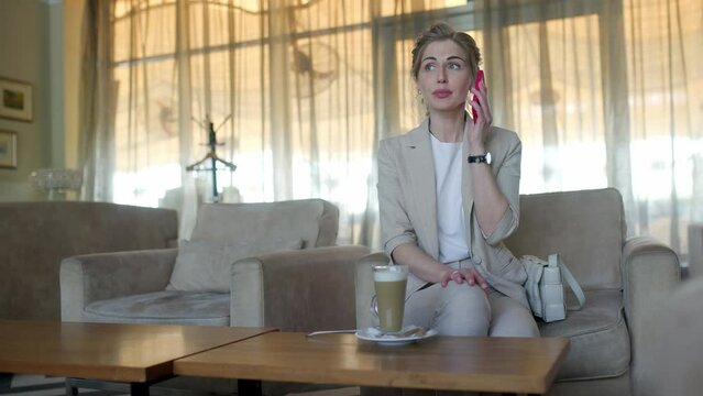 Young woman in cafe works with a smartphone. girl in a cafe uses a tablet and drinks delicious aromatic coffee. woman chatting, drinking coffee and relaxing. close-up.