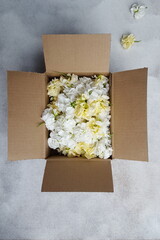 Lieferung  Geschenk Karton gefüllt mit weißen und gelben Blüten auf grauem Untergrund Levkoje...