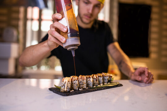 Serious young man adding sauce on gunkan maki