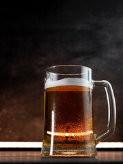 cold beer mug in drops of water on a dark table,