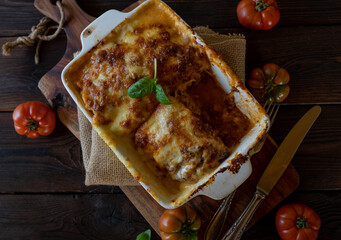 Lasagne with bolognese sauce and bechamel sauce with mozzarella cheese topping on rustic and wooden table from above