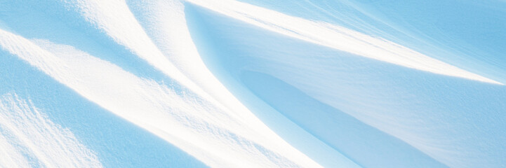 Snow texture. Wind sculpted patterns on snow surface. Wind in the tundra and in the mountains on the surface of the snow sculpts patterns and ridges (sastrugi). Arctic, Polar region. Winter background