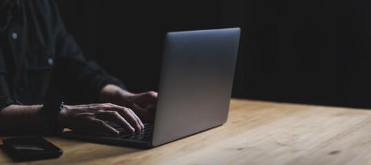 Man hands and Laptop on wooden table. Copy space on black background.