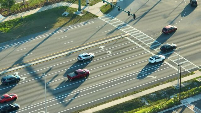 Top view of wide road with moving cars at intersection with traffic lights. City transportation in the USA. American town traffic from above