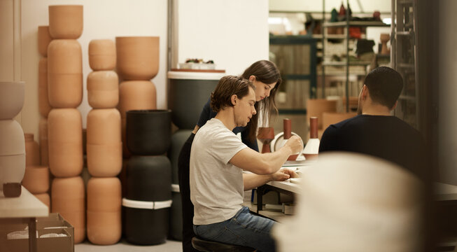 Ceramics designers talking together at a studio table