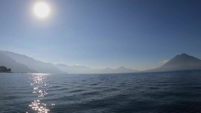 Traveling by motorboat across Lake Atitlan with Volcano in distance, Guatemala, Central America