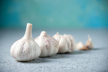 front view fresh garlics lined on light blue background vegetable food pepper sour plant seasoning greens